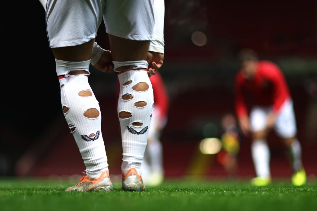 Footballer with holes cut in the back of his socks.